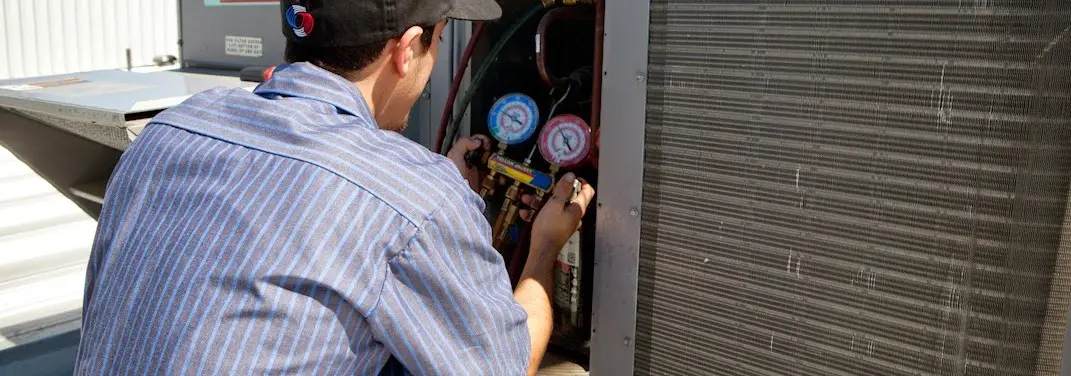HVAC technician servicing a condenser unit in Warsaw